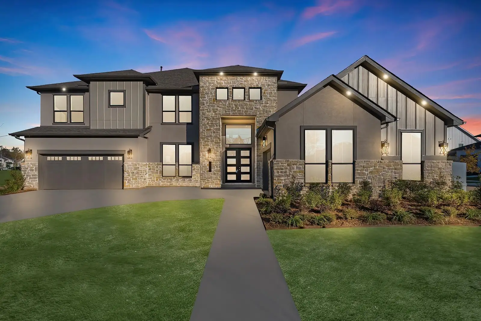 A stone and stucco two-story home lit at dusk