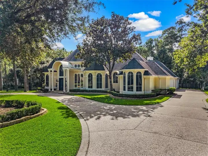 A single-story home with columns among tall trees