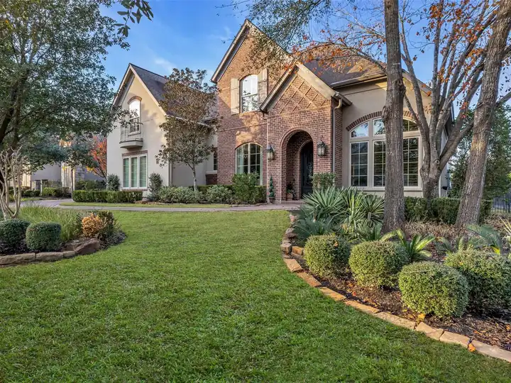 A brick and stucco home among mature trees